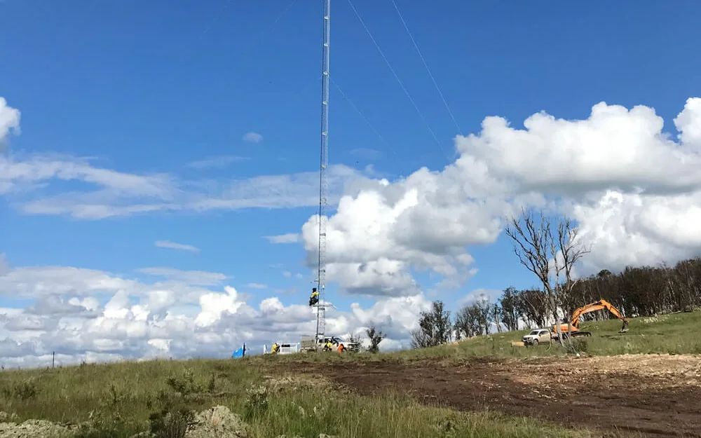 Lattice met mast installation with site vehicles on a ridge